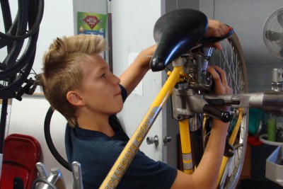 12-year-old Atticus Ryan attaches pedals to a used bike